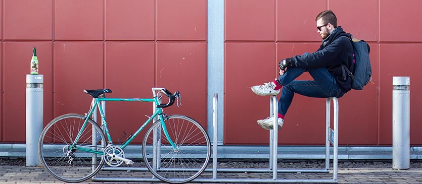 Junger Fahrradkurier macht Pause am Fahrradständer