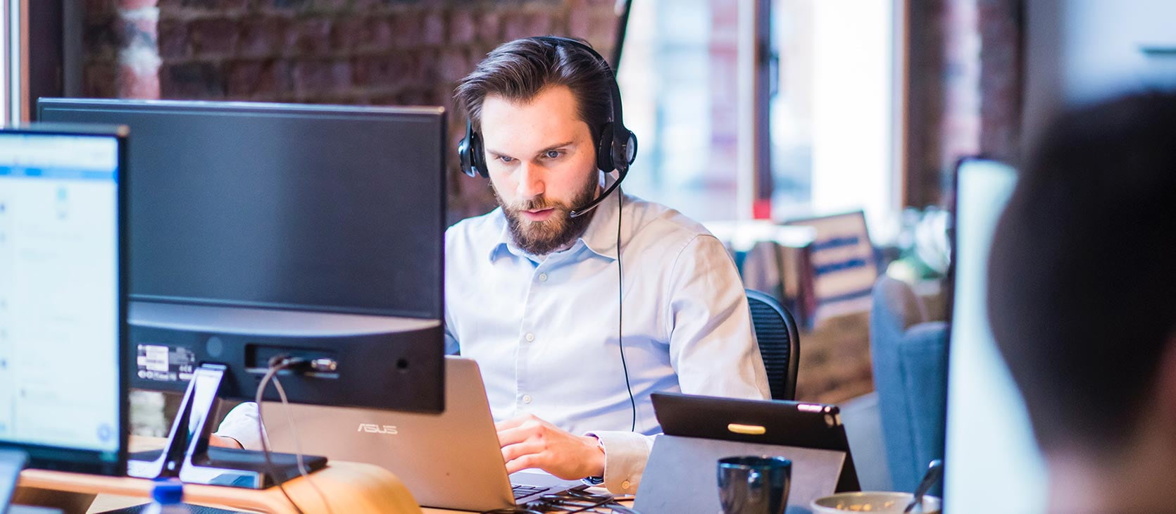 Junger Mann mit Headset telefoniert mit Kunden
